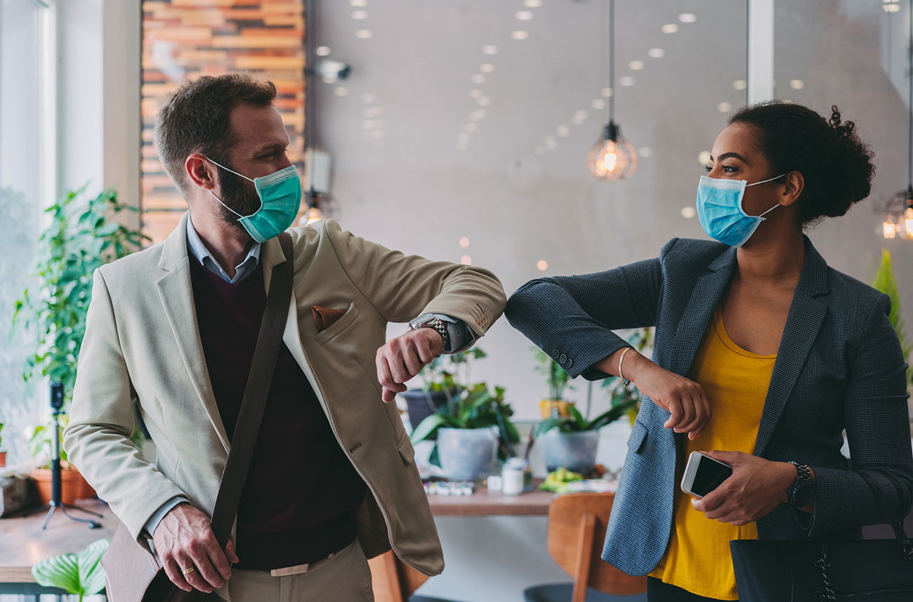 co-workers bumping elbows and wearing face masks