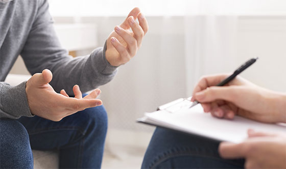 Therapist writing with pen on clipboard