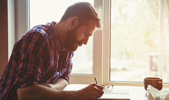Man writing in notebook at home