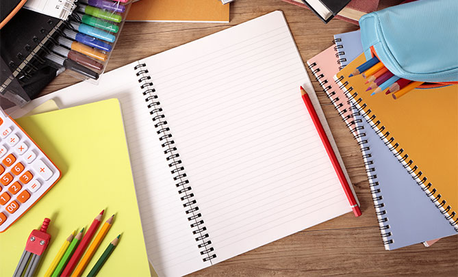 School supplies on desk notebooks and colored pencils