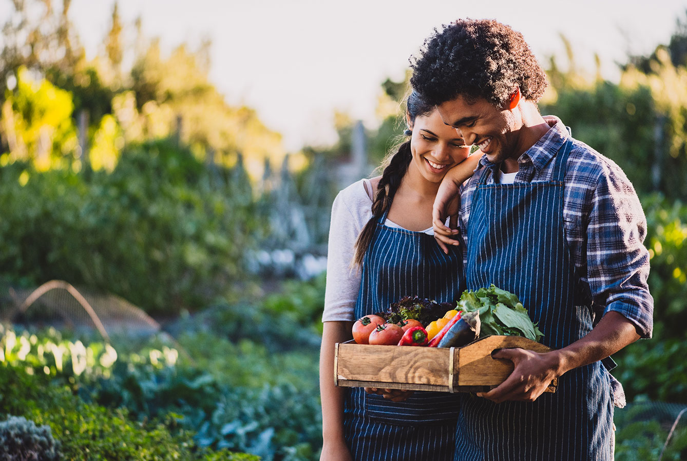 Couple in home garden with vegetable harvest